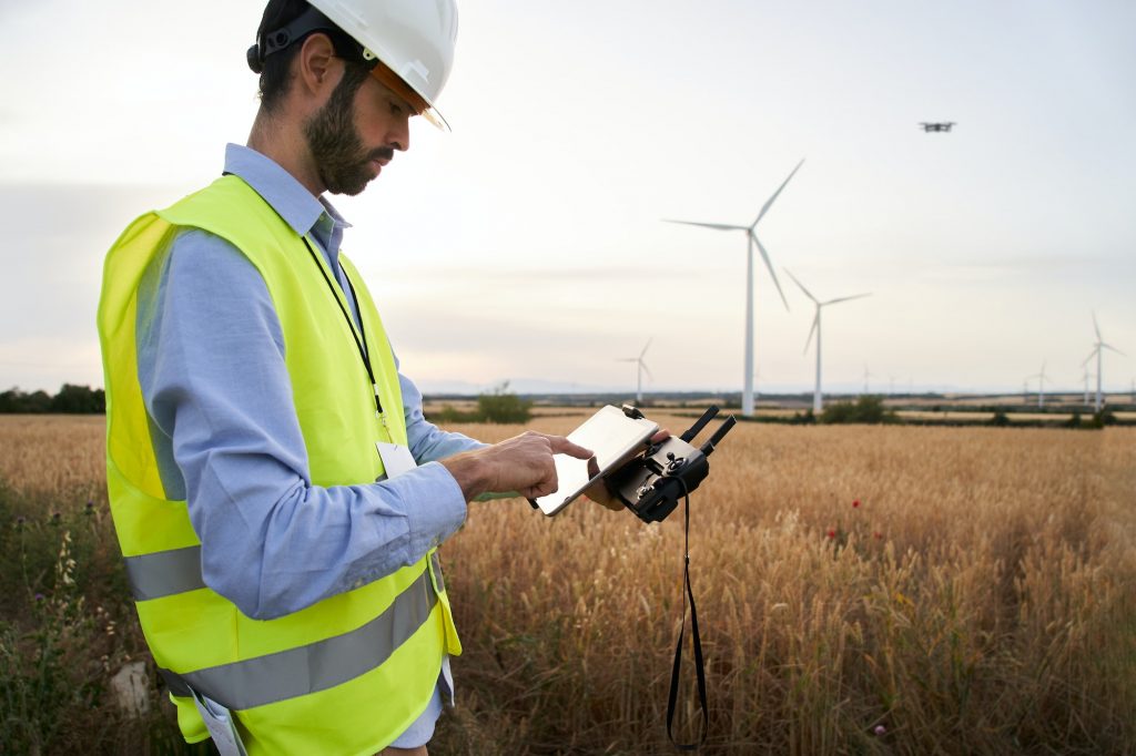 European engineer focused on using drone to inspect wind farm. People and technology in workplace.